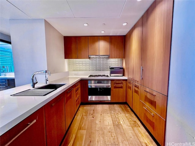 kitchen featuring sink, stainless steel appliances, light hardwood / wood-style flooring, backsplash, and kitchen peninsula