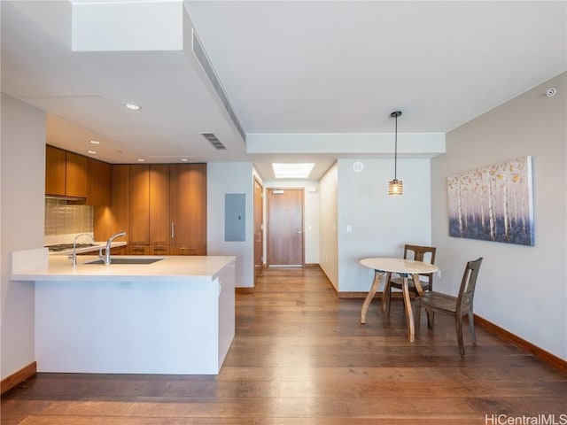 kitchen featuring brown cabinets, wood-type flooring, light countertops, visible vents, and a sink