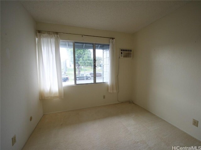 carpeted spare room featuring a wall unit AC and a textured ceiling