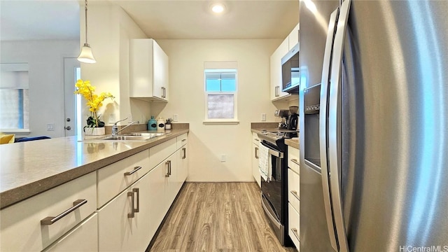 kitchen with decorative light fixtures, sink, white cabinetry, and stainless steel appliances