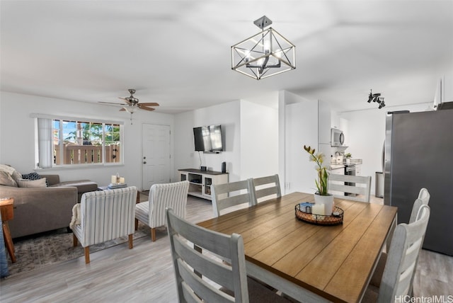 dining space with ceiling fan with notable chandelier and light wood-type flooring