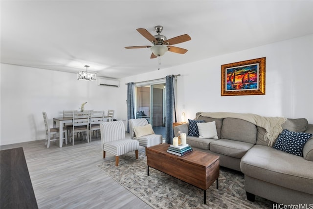 living room with a wall unit AC, light hardwood / wood-style floors, and ceiling fan with notable chandelier