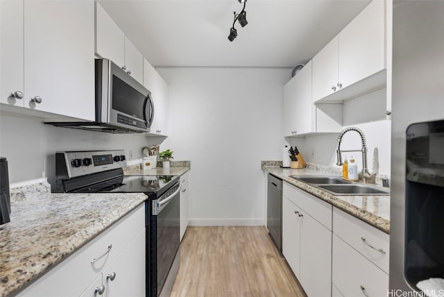 kitchen with white cabinets, appliances with stainless steel finishes, light wood-type flooring, and sink