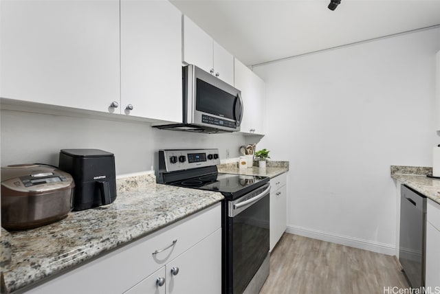 kitchen with white cabinets, light hardwood / wood-style floors, light stone countertops, and stainless steel appliances