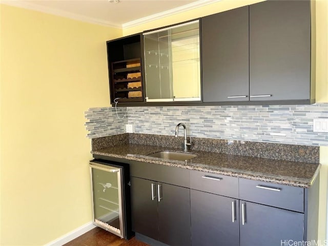 kitchen with sink, beverage cooler, tasteful backsplash, dark stone countertops, and ornamental molding