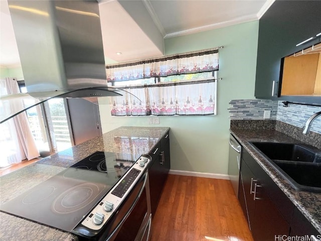 kitchen featuring stove, dark stone counters, ornamental molding, island range hood, and sink