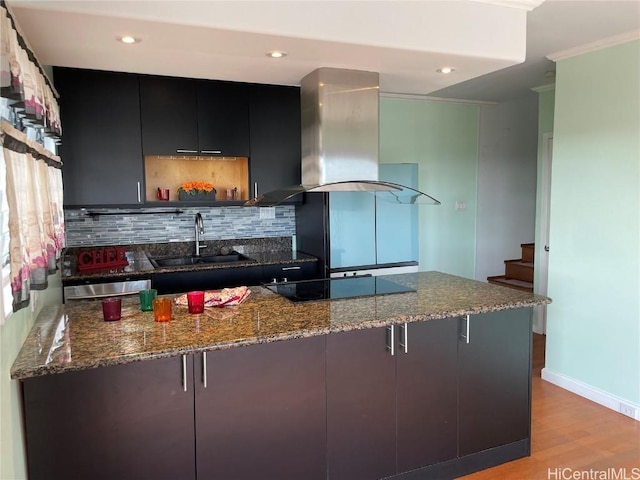 kitchen featuring a breakfast bar, sink, kitchen peninsula, island range hood, and black electric stovetop