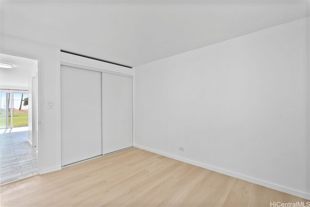 unfurnished bedroom with a closet and light hardwood / wood-style floors