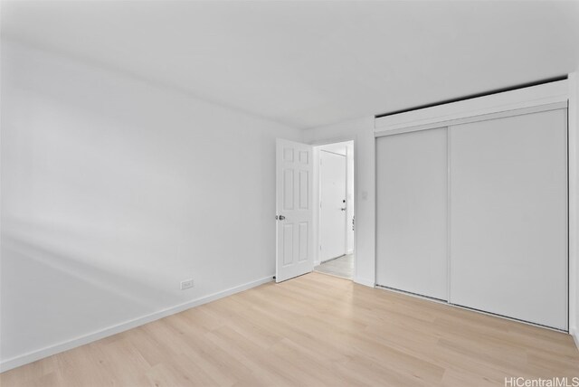 unfurnished bedroom with a closet and light wood-type flooring