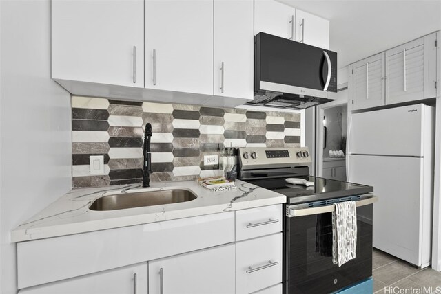 kitchen featuring sink, tasteful backsplash, light stone counters, white cabinetry, and stainless steel appliances