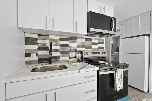 kitchen with sink, stainless steel appliances, light stone counters, tasteful backsplash, and white cabinets