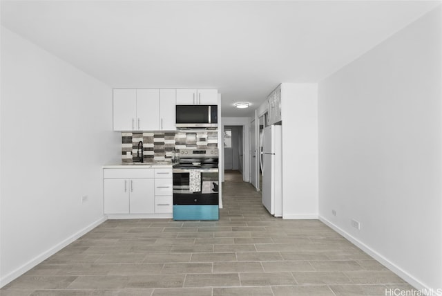 kitchen featuring decorative backsplash, appliances with stainless steel finishes, white cabinets, and sink