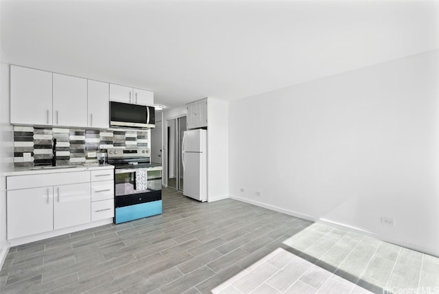 kitchen featuring white cabinetry, sink, light hardwood / wood-style flooring, decorative backsplash, and appliances with stainless steel finishes