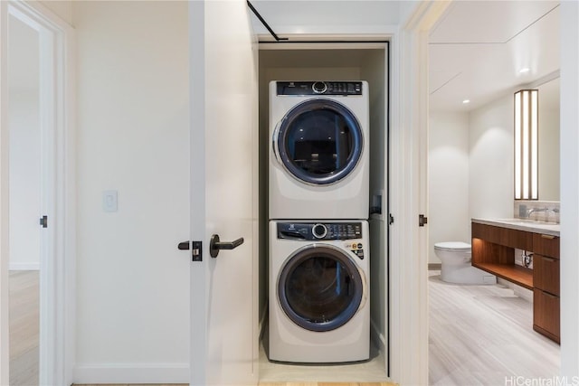 washroom featuring light hardwood / wood-style flooring and stacked washer / dryer