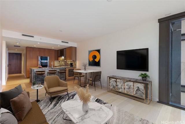 living room with light wood-type flooring and beverage cooler