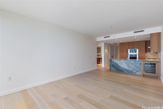 unfurnished living room with light wood-type flooring and wine cooler