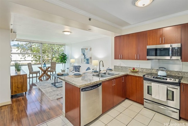 kitchen with kitchen peninsula, light stone countertops, ornamental molding, stainless steel appliances, and sink