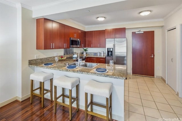 kitchen featuring kitchen peninsula, appliances with stainless steel finishes, crown molding, and sink