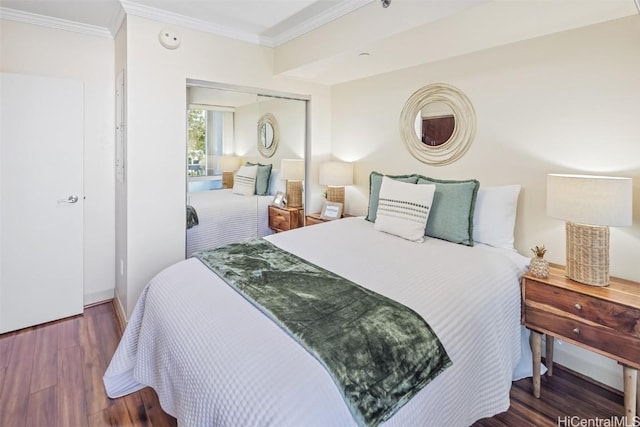 bedroom with a closet, baseboards, ornamental molding, and wood finished floors