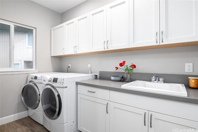 laundry room featuring dark hardwood / wood-style flooring, sink, washing machine and dryer, and cabinets