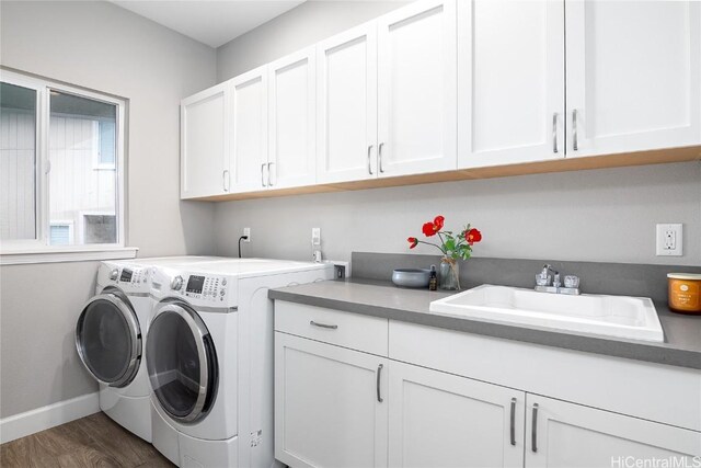 laundry room featuring cabinet space, baseboards, dark wood-style floors, independent washer and dryer, and a sink