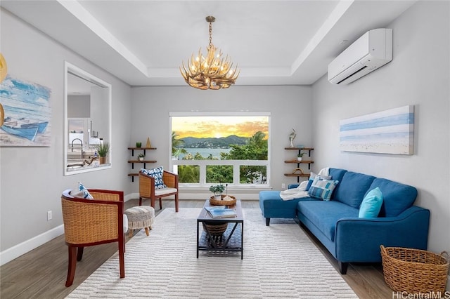 sitting room with hardwood / wood-style flooring, a wall mounted air conditioner, a chandelier, and a tray ceiling