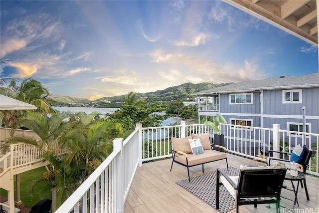 deck at dusk featuring an outdoor living space and a water and mountain view