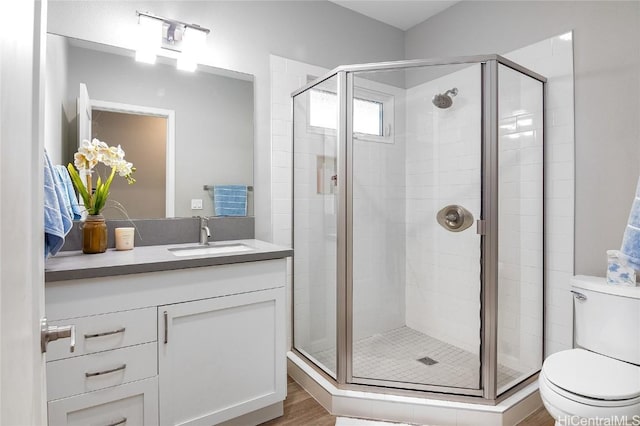 bathroom featuring an enclosed shower, vanity, hardwood / wood-style flooring, and toilet