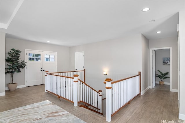 corridor featuring baseboards, recessed lighting, an upstairs landing, and light wood-style floors