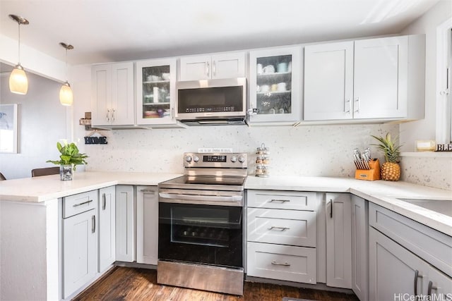 kitchen with stainless steel appliances, a peninsula, light countertops, backsplash, and pendant lighting