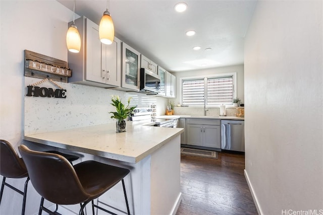 kitchen featuring decorative light fixtures, kitchen peninsula, stainless steel appliances, and a kitchen bar