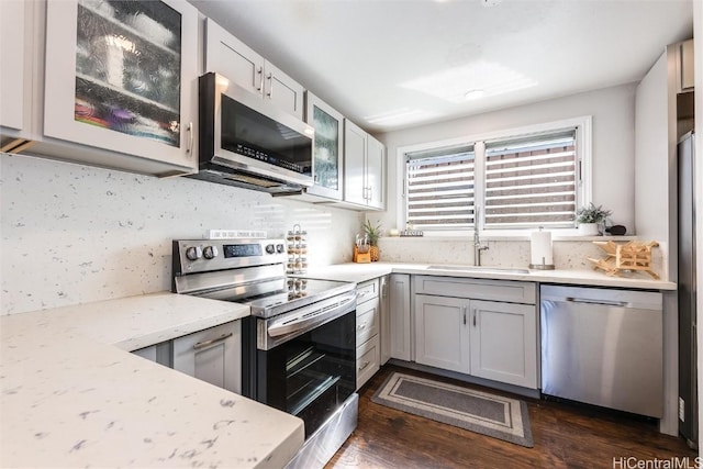 kitchen featuring decorative backsplash, sink, appliances with stainless steel finishes, dark hardwood / wood-style flooring, and light stone counters