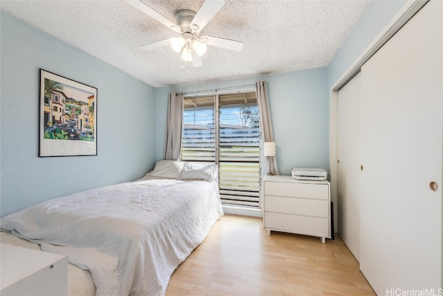 bedroom with ceiling fan, a closet, a textured ceiling, and light hardwood / wood-style floors