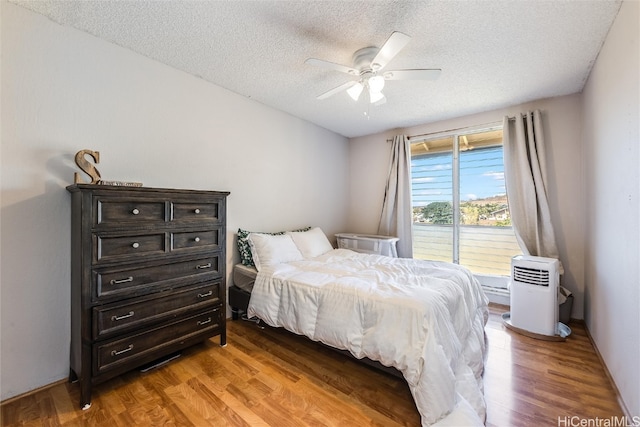 bedroom with a textured ceiling, ceiling fan, and light hardwood / wood-style flooring