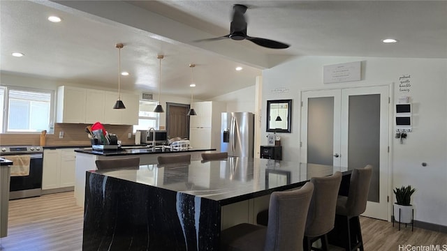 kitchen with white cabinetry, appliances with stainless steel finishes, backsplash, lofted ceiling, and a kitchen island