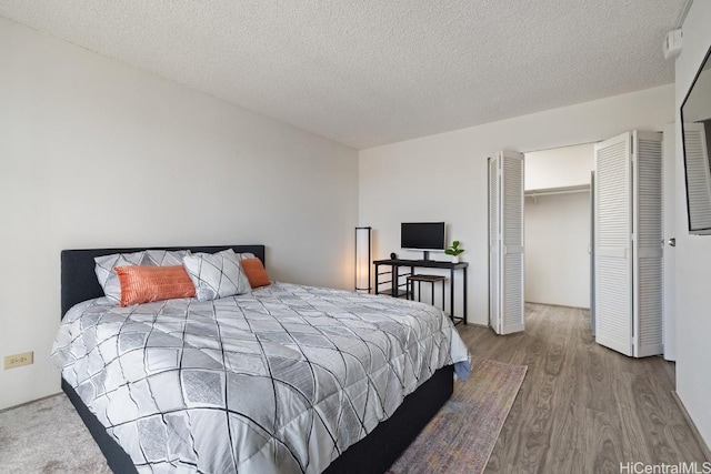 bedroom with hardwood / wood-style floors, a textured ceiling, and a closet