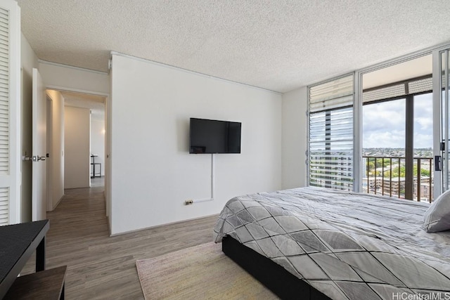 bedroom featuring hardwood / wood-style floors, floor to ceiling windows, a textured ceiling, and access to outside