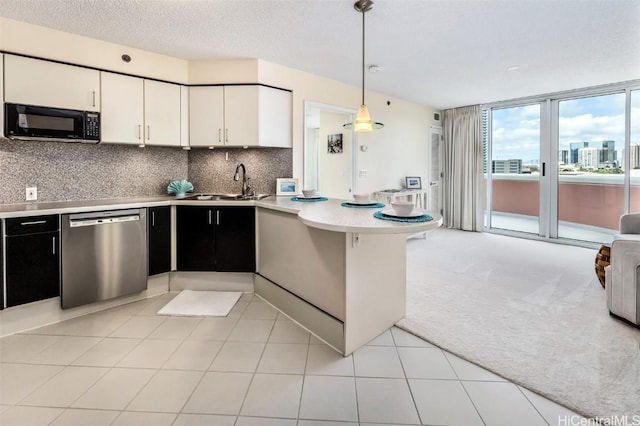 kitchen with dishwasher, sink, hanging light fixtures, light colored carpet, and white cabinets