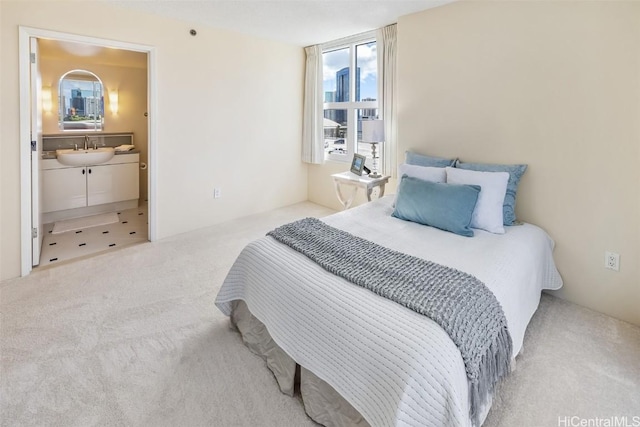 carpeted bedroom featuring ensuite bath and sink