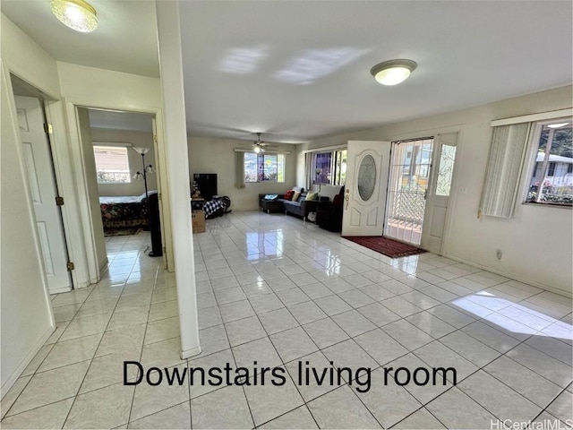 tiled entrance foyer with ceiling fan and a healthy amount of sunlight