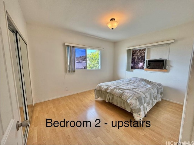 bedroom with a closet, light hardwood / wood-style flooring, and cooling unit