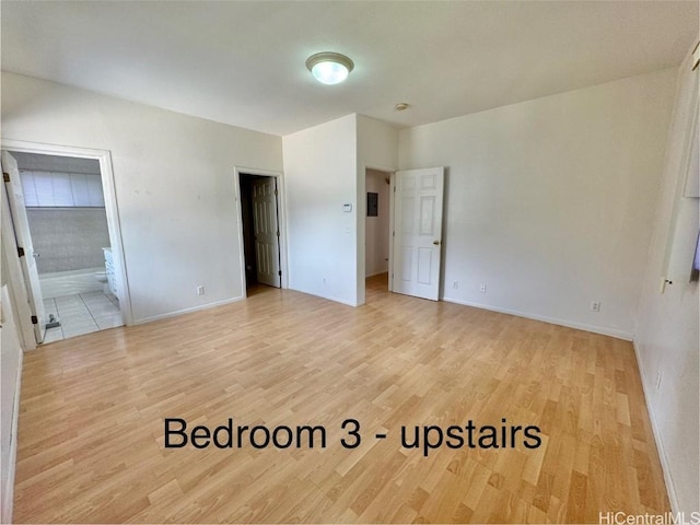 unfurnished bedroom featuring ensuite bathroom and light hardwood / wood-style floors