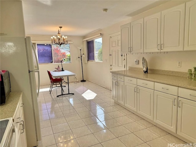 kitchen with white cabinetry, hanging light fixtures, an inviting chandelier, white refrigerator, and light tile patterned floors