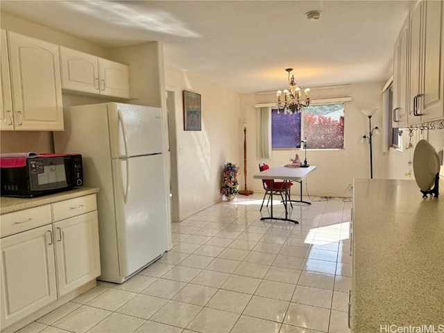 kitchen with hanging light fixtures, light tile patterned floors, a notable chandelier, white fridge, and white cabinets