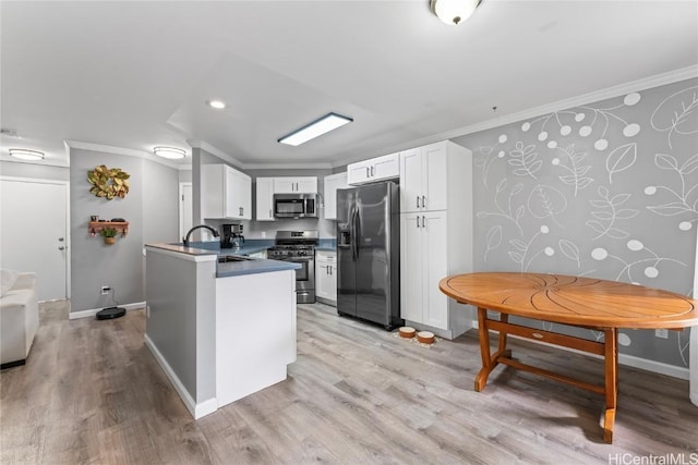 kitchen with kitchen peninsula, ornamental molding, white cabinets, and stainless steel appliances