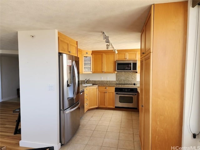 kitchen with backsplash, sink, light tile patterned floors, light brown cabinetry, and stainless steel appliances