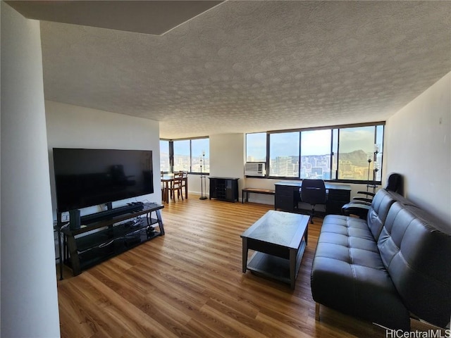 living room with cooling unit, wood-type flooring, and a textured ceiling