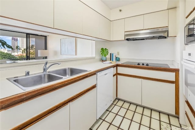 kitchen featuring white cabinetry, sink, light tile patterned floors, and white appliances