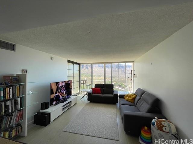 living room with hardwood / wood-style flooring, floor to ceiling windows, and a textured ceiling