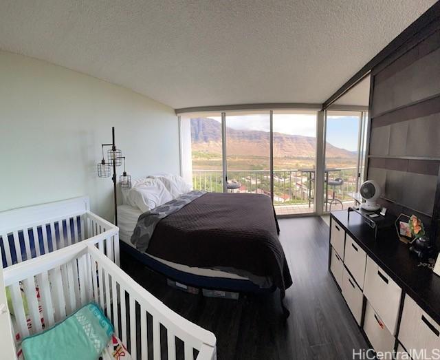 bedroom featuring expansive windows, dark hardwood / wood-style floors, a mountain view, a textured ceiling, and access to outside